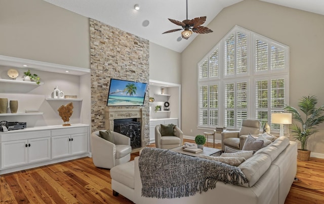 living room featuring a fireplace, a healthy amount of sunlight, built in features, and light wood-type flooring