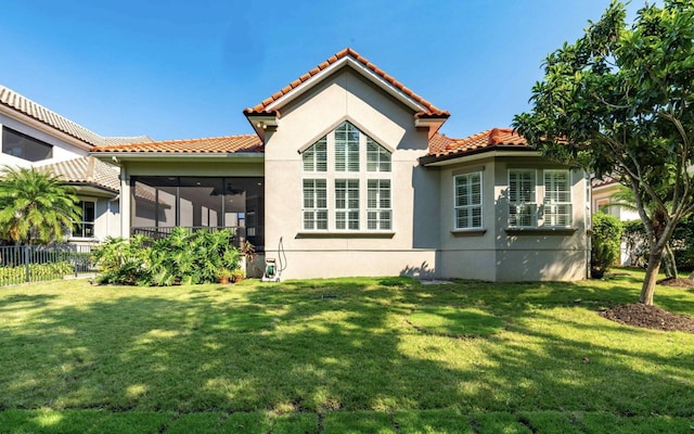 rear view of property featuring a lawn and a sunroom