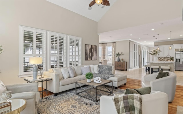 living room featuring light hardwood / wood-style floors, high vaulted ceiling, ceiling fan, and crown molding