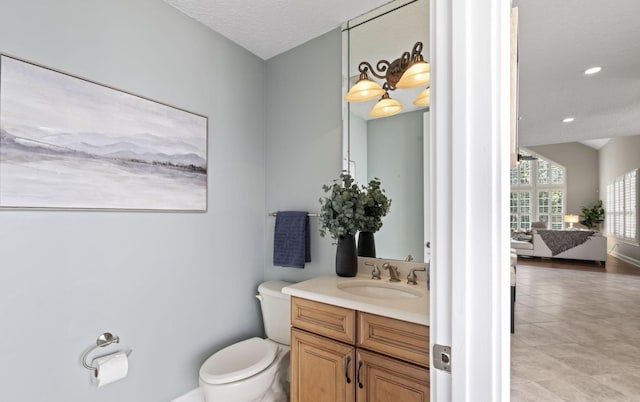 bathroom with tile patterned floors, vanity, a textured ceiling, and toilet