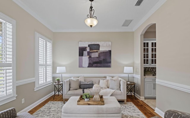 living room with a wealth of natural light, crown molding, and light wood-type flooring