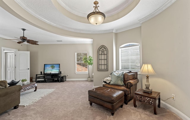 carpeted living room with a tray ceiling, ceiling fan, and ornamental molding