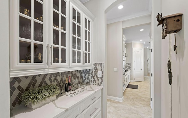 bar with white cabinets, tasteful backsplash, ornamental molding, and light tile patterned flooring