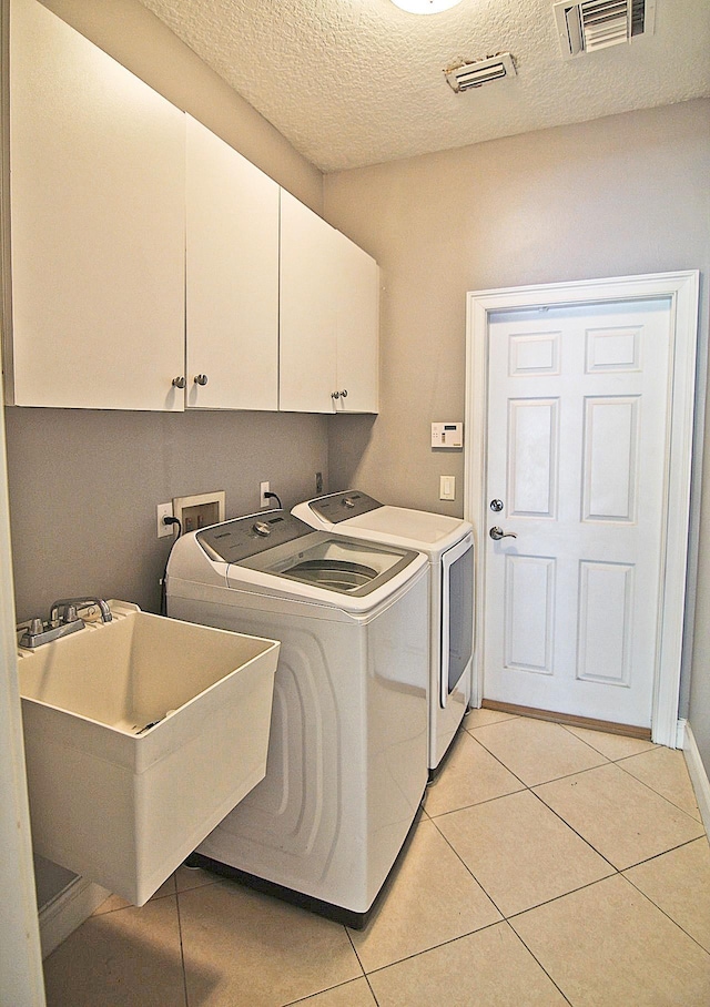30 Fortress Pl, Palm Coast, FL 32137 - washroom with cabinet space, washer and dryer, a textured ceiling, and light tile patterned flooring