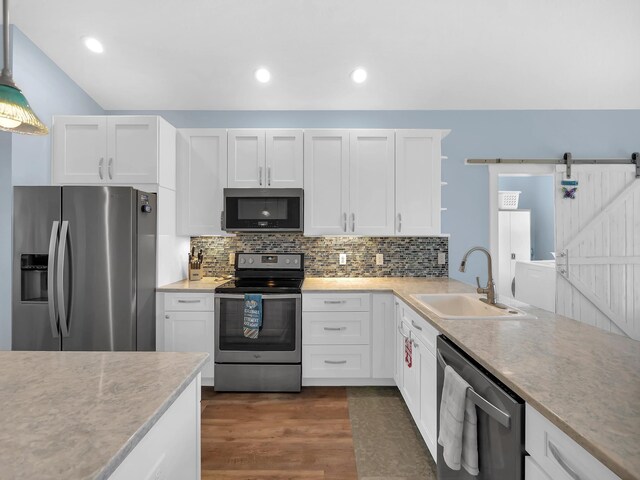 519 Arricola Ave, Saint Augustine, FL 32080 - kitchen with open shelves, white cabinets, a barn door, stainless steel appliances, and a sink