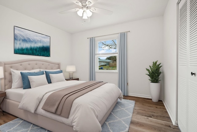 bedroom featuring ceiling fan, baseboards, a closet, and wood finished floors