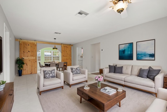 living room featuring light tile patterned floors, a barn door, visible vents, and arched walkways