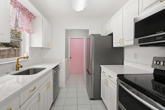 kitchen with light tile patterned floors, light stone counters, stainless steel appliances, a sink, and white cabinets