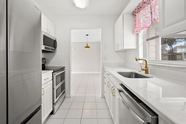 kitchen featuring light tile patterned floors, white cabinets, appliances with stainless steel finishes, light stone countertops, and a sink