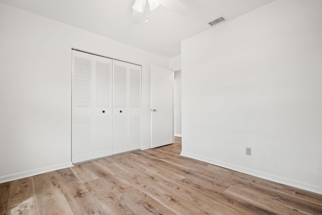 unfurnished bedroom with a closet, wood finished floors, visible vents, and baseboards