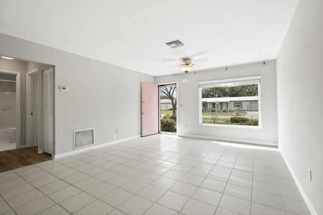 spare room with a ceiling fan, visible vents, baseboards, and light tile patterned floors