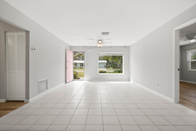 empty room featuring light tile patterned floors, baseboards, visible vents, and a ceiling fan