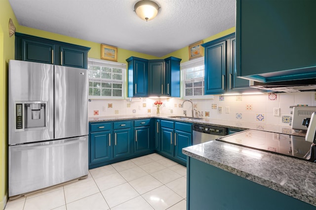 kitchen with a wealth of natural light, blue cabinets, sink, and appliances with stainless steel finishes