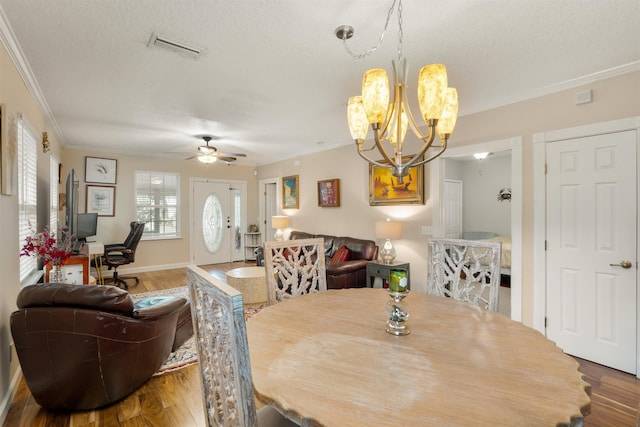 dining area featuring a textured ceiling, crown molding, ceiling fan with notable chandelier, and hardwood / wood-style flooring