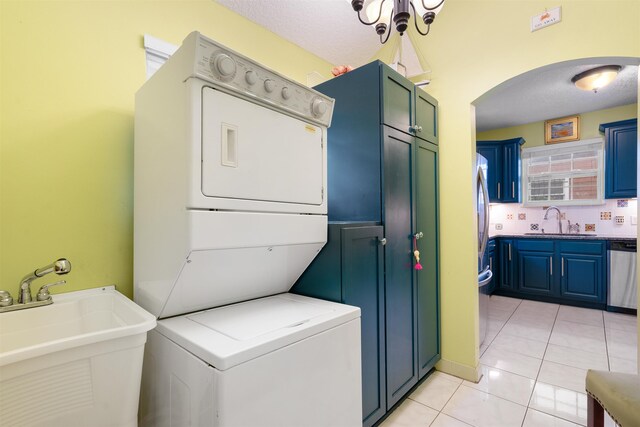 162 Martin Luther King Ave, Saint Augustine, FL 32084 - laundry area featuring stacked washer / dryer, arched walkways, light tile patterned floors, and cabinet space