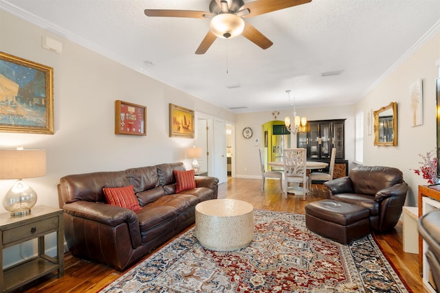 living room with crown molding, ceiling fan with notable chandelier, and hardwood / wood-style flooring