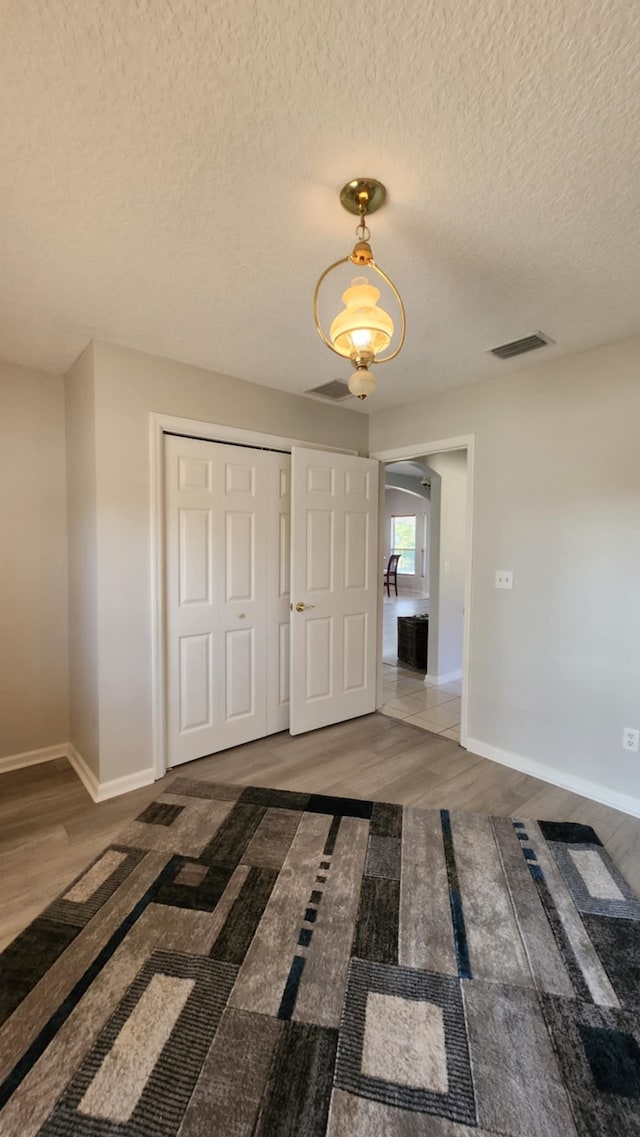 interior space featuring baseboards, a closet, wood finished floors, arched walkways, and a textured ceiling