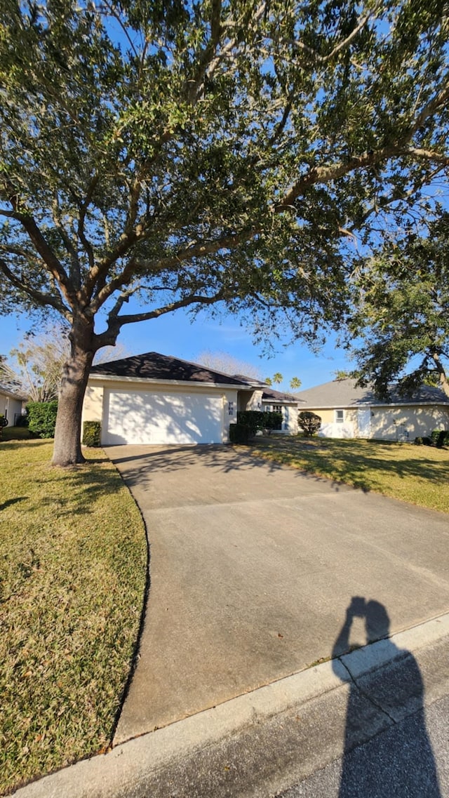 view of front facade featuring an attached garage, concrete driveway, and a front yard