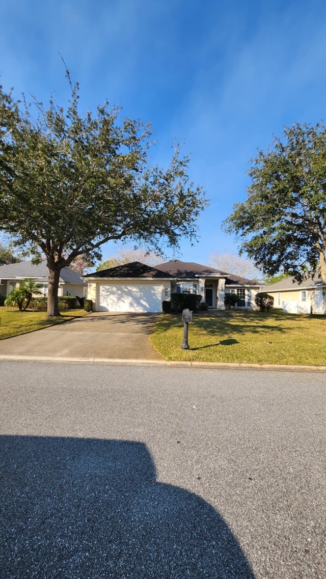 view of front facade featuring concrete driveway, an attached garage, and a front lawn