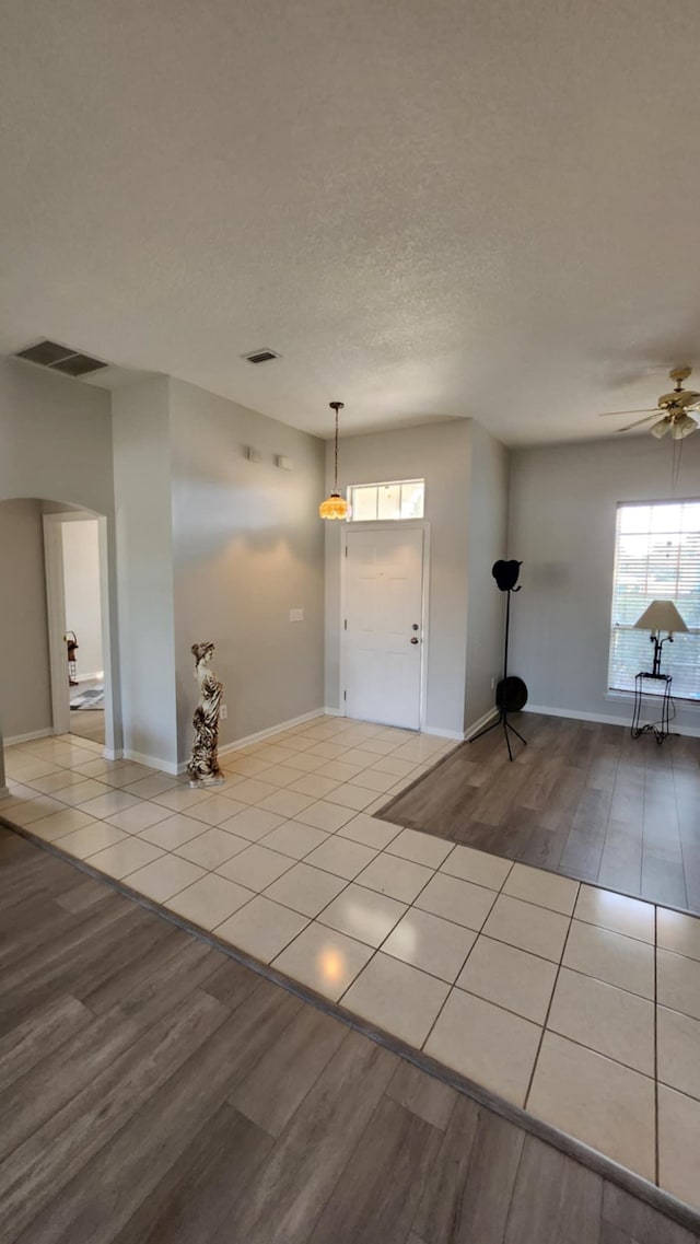 tiled entrance foyer with ceiling fan and baseboards