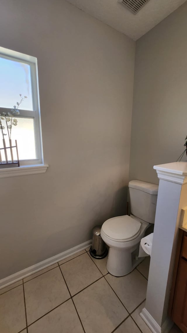 half bathroom with toilet, vanity, tile patterned floors, and baseboards
