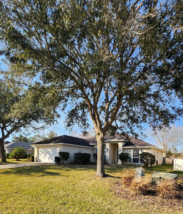 ranch-style house with a garage, a front lawn, stucco siding, and driveway