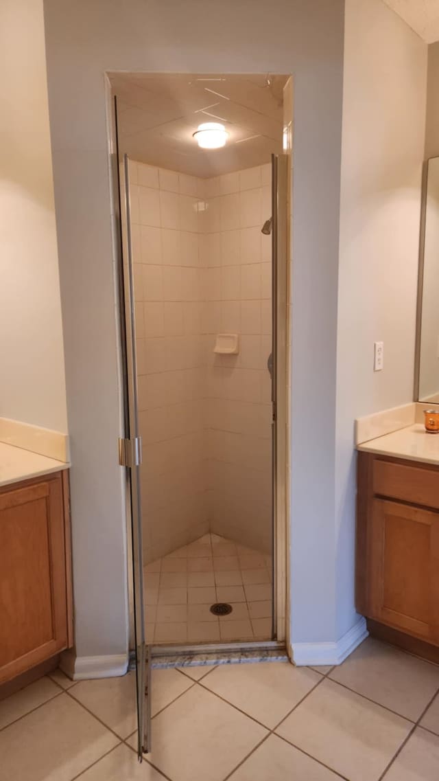 full bathroom with vanity, a shower stall, tile patterned flooring, and baseboards