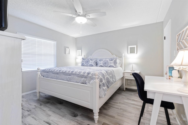 bedroom with ceiling fan, light hardwood / wood-style flooring, and a textured ceiling