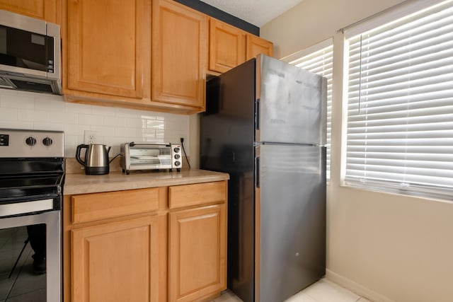 9 Kings Colony Ct Unit 9, Palm Coast, FL 32137 - kitchen featuring stainless steel appliances, backsplash, light countertops, light tile patterned floors, and light brown cabinets