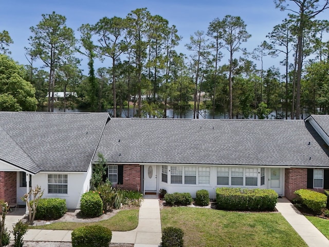 9 Kings Colony Ct Unit 9, Palm Coast, FL 32137 - view of front of property with roof with shingles, a front lawn, a water view, and brick siding