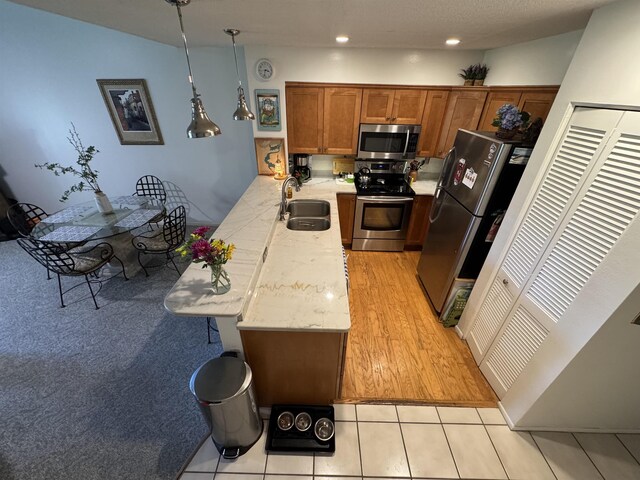 66 Village Del Lago Cir, Saint Augustine, FL 32080 - kitchen featuring a sink, a kitchen breakfast bar, a peninsula, brown cabinetry, and stainless steel appliances