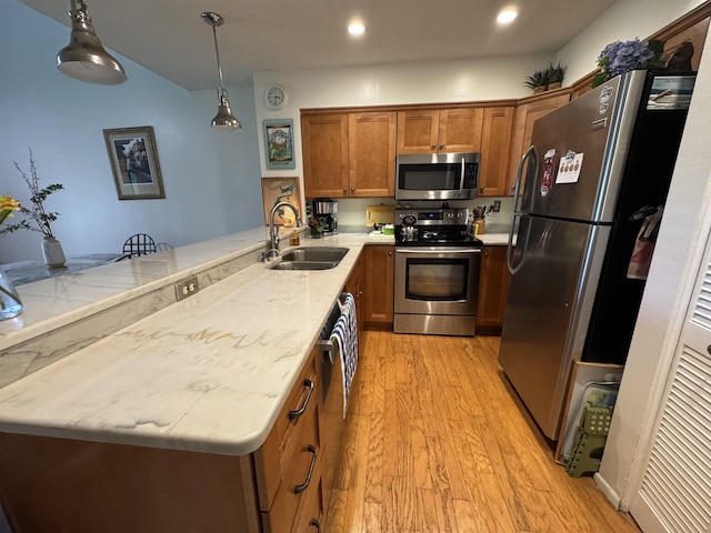 66 Village Del Lago Cir, Saint Augustine, FL 32080 - kitchen with a sink, a peninsula, brown cabinets, light wood-type flooring, and stainless steel appliances