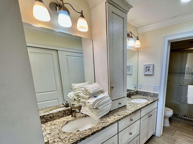 bathroom with a shower stall, a sink, toilet, and crown molding