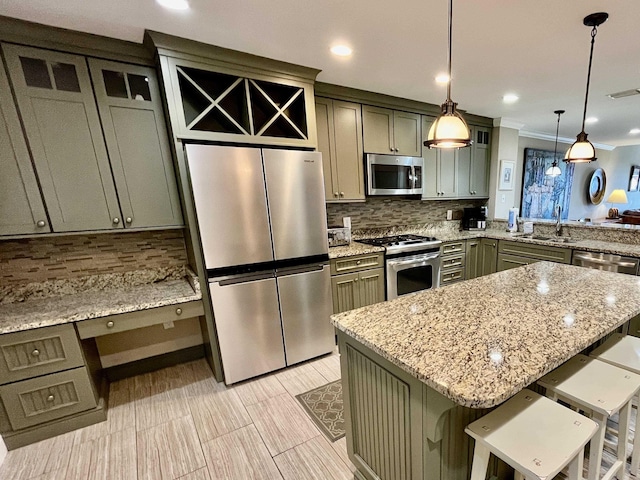 kitchen featuring a center island, decorative light fixtures, appliances with stainless steel finishes, a sink, and a kitchen breakfast bar