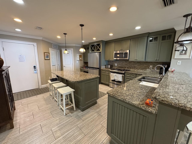 kitchen with appliances with stainless steel finishes, decorative light fixtures, a kitchen island, and visible vents