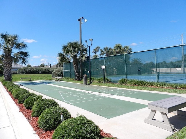 view of community featuring a tennis court, fence, and shuffleboard