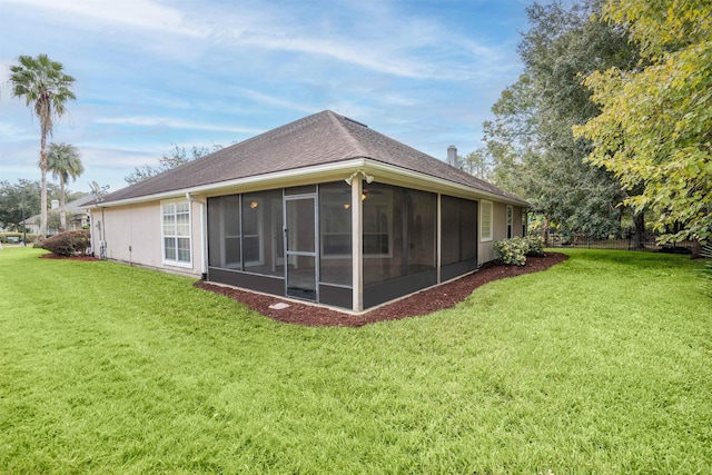 rear view of house with a lawn and a sunroom