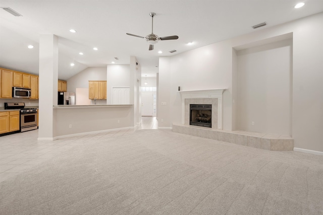 unfurnished living room with ceiling fan, lofted ceiling, light carpet, and a tile fireplace