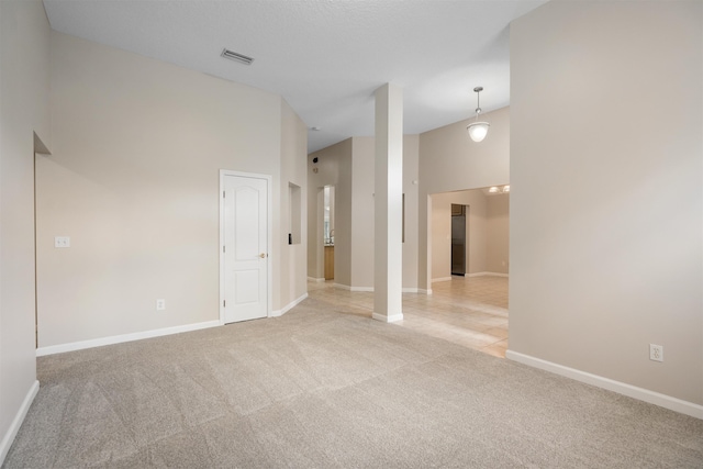 unfurnished room featuring light carpet and a towering ceiling