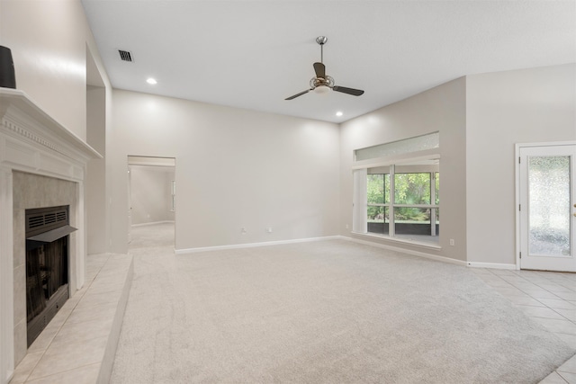 unfurnished living room featuring ceiling fan, light colored carpet, and a tiled fireplace