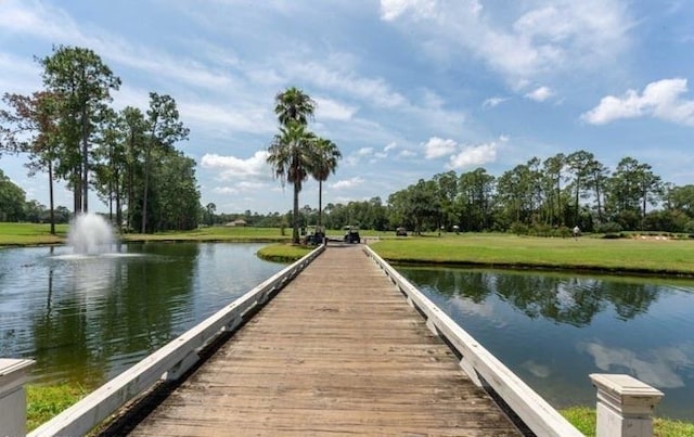 dock area with a lawn and a water view