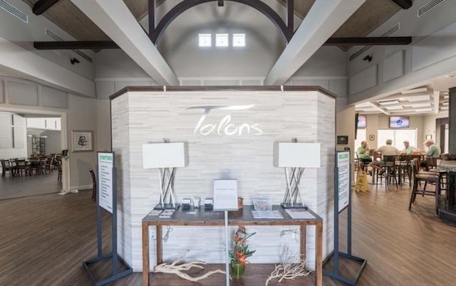 interior space featuring beam ceiling, wood-type flooring, and a high ceiling