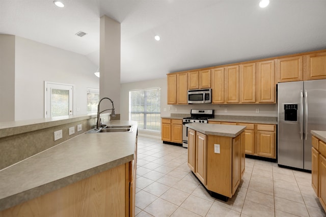 kitchen with a center island, lofted ceiling, sink, light tile patterned floors, and stainless steel appliances