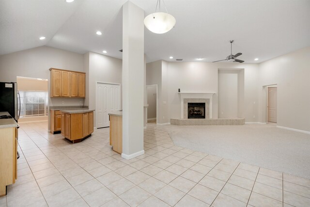 carpeted living room with a tile fireplace, high vaulted ceiling, and ceiling fan