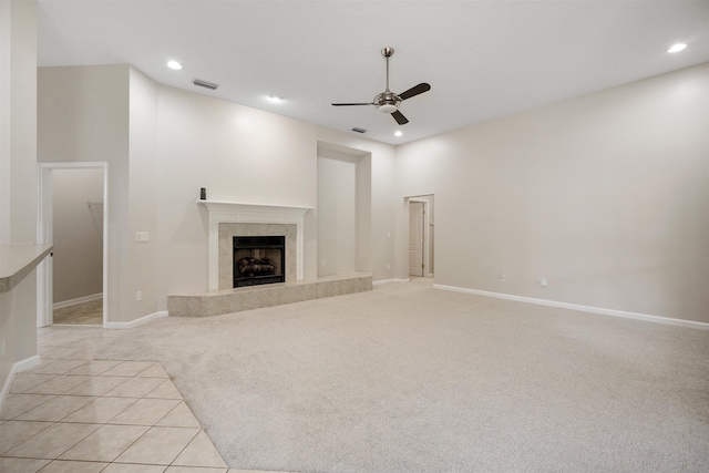 unfurnished living room featuring a tile fireplace, light colored carpet, and ceiling fan