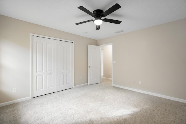 unfurnished bedroom featuring light carpet, a closet, and ceiling fan