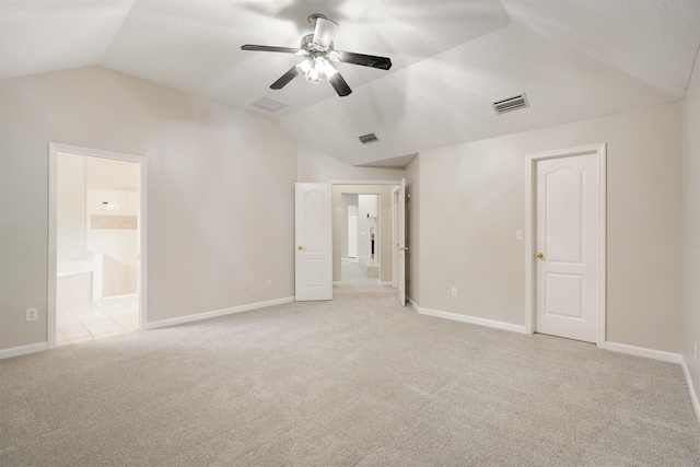 unfurnished bedroom with connected bathroom, ceiling fan, light colored carpet, a textured ceiling, and vaulted ceiling