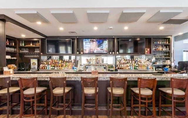 bar featuring dark hardwood / wood-style floors and light stone counters