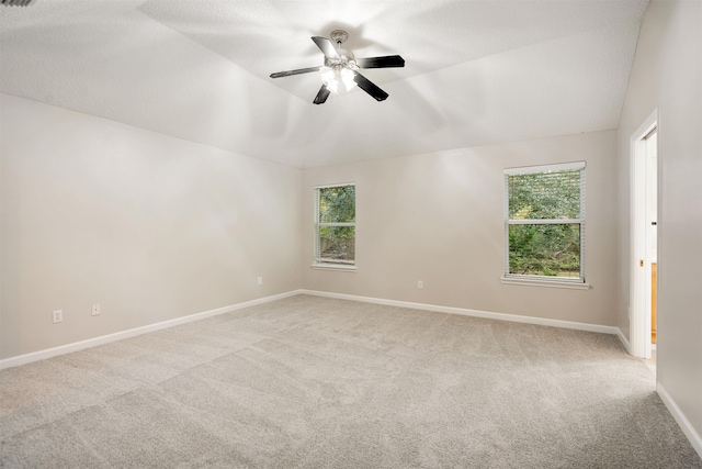 spare room featuring light carpet, a wealth of natural light, and lofted ceiling