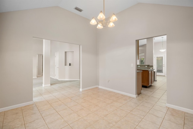 tiled spare room with high vaulted ceiling and an inviting chandelier